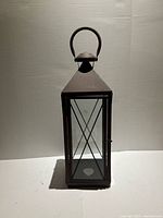 Full view of metal and glass lantern showing frame, glass panes, X-braces and handle