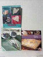 Front covers of three metal craft project books displayed upright