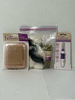 Front view of all items: foam block, needle tool, bag of wool roving