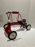 Full view of red Radio Flyer Scoot About tricycle showing frame, wheels, handlebar and seat