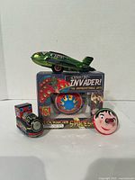 Group shot showing all four tin toys including boxed UFO, plane, train, and spinning top