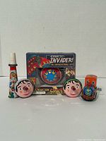 All five tin toys including boxed Erratic Invader UFO, two Pinocchio tops, orange train, tin whistle