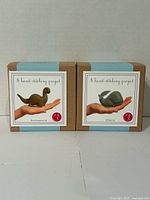 Front view of two unopened Threadfollower felt hand-stitching kits (Brontosaurus and Whale) in cardboard boxes.