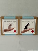Front view of two unopened felt hand-stitching kits showing rabbit and penguin designs