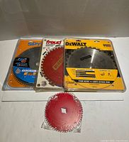 Four circular saw blades: packaged Spyder, Freud Diablo, DeWalt, and loose small red blade