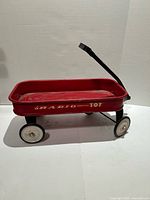 Profile view of red Radio Tot wagon showing handle, wheels and side lettering
