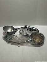 Two silver-tone wall lights in plastic bag showing bowl shades, cords, and switches