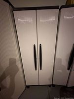 Front view of closed cabinet showing ribbed doors and black handles