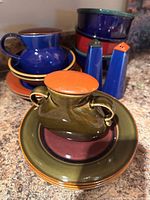Side angle showing mugs, saucer, shakers and plate with jar