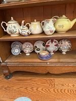 Shelf view showing all teapots on top and teacup sets on bottom