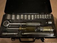 Open metal case showing sockets, ratchet, spinner handle, extensions