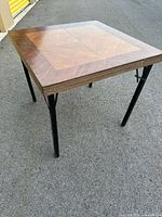 Three-quarter view of table showing wood veneer top and black metal legs