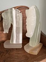 Front and side view of both white onyx horse head bookends on wooden shelf
