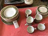Stack of assorted plates and group of cups showing pattern and quantity