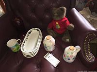 All items in lot: stack of five platters, two jugs, mug, burgundy glass vase, teddy bear