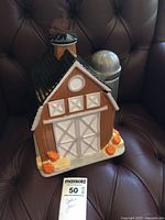 Front view of Cheryl's Cookies barn cookie jar on chair