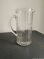 Full view of pitcher showing handle, ribbing, droplet details