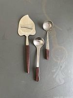 Front view of cheese slicer and two spoons showing rosewood handles and stainless heads