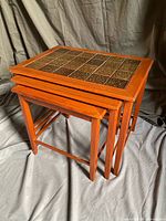 Three teak nesting tables stacked, showing tile top of upper table