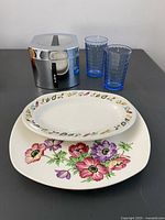 All items grouped: canister, two glasses, oval plate, square floral plate