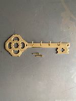 Front view of brass key-shaped rack with screws displayed