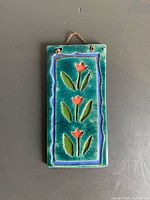 Front view of ceramic plaque showing tulip cut-outs, glaze colors, hanging holes with cord