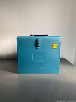 Front view of blue metal slide box showing latch and sticker
