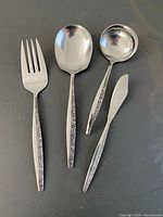 Front view of four matching stainless serving pieces