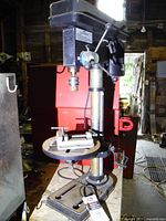Full view of drill press on bench with vise and belt