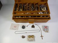 Overall view of tackle box open showing trays full of jewellery plus separate pieces laid out in front