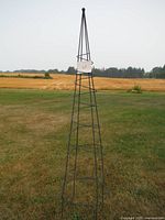 Full view of metal spiral garden obelisk standing on lawn