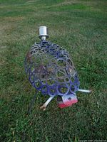 Side view of scrap metal insect sculpture on grass showing overall form