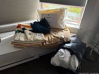 Stack of blankets, comforter, packaged pillow and bagged duvet