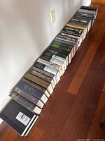 Full row of approximately 55 books lined along hardwood floor