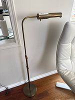 Full view of adjustable brass floor lamp beside chair