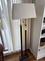 Full view of floor lamp beside window, shows shade, columns, base