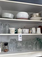 Cupboard shelves with bowls, mugs, tumblers and stemware