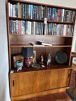 Front view showing upper shelves filled with books and lower sliding door cabinet