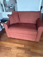 Front angled view of red La-Z-Boy sleeper chair showing upholstery and pillow