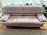 Front view of mauve leather sofa showing cushions and legs