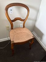 Front angle of wood frame side chair showing wicker seat and curved backrest
