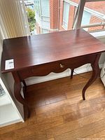 Full view of wood side table showing top, legs, drawer