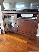 Front view of console showing glass door, wood door, and open shelf