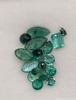 Loose emerald gemstones assorted shapes on white background