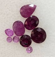 Nine loose rubies laid out on white background