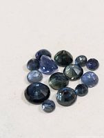 Group of mixed-color faceted sapphire gemstones on neutral background