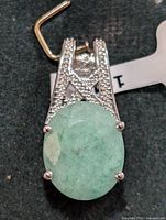 Front view of silver pendant with oval green dyed emerald stone