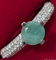 close-up of the silver ring showing round emerald and pavé CZ on band