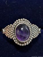 Front view of silver ring with central amethyst cabochon