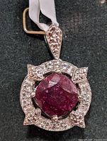 Front view of pendant showing central dyed ruby topaz and surrounding clear stones